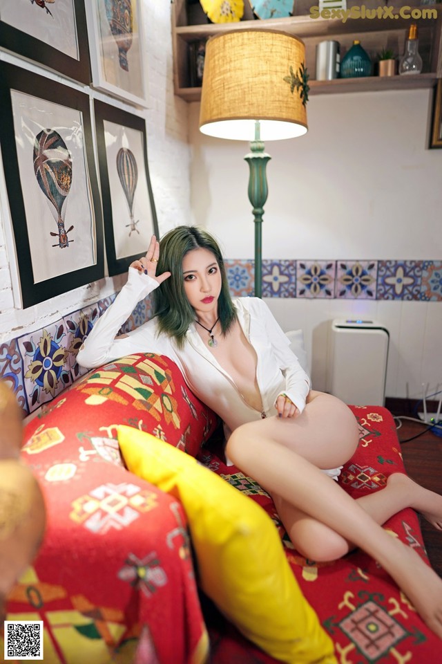 A woman sitting on top of a red couch next to a lamp.
