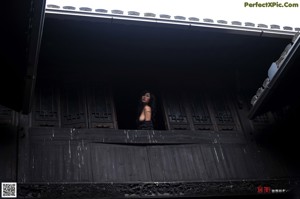 A naked woman sitting on the ground next to a stone bowl.