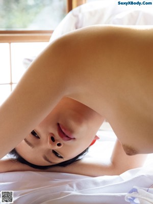 A naked woman laying on a tatami mat in a room.