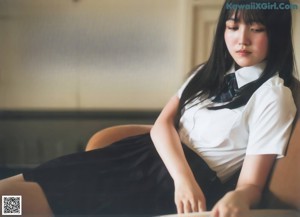 A woman with long black hair leaning against a wall.