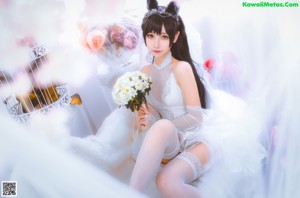 A woman in a white dress sitting on a white chair.