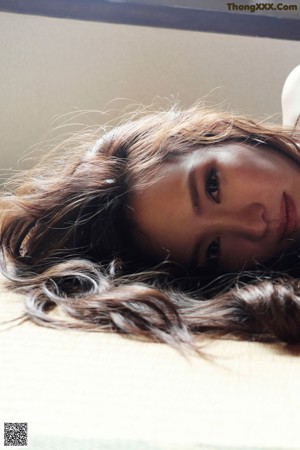 A naked woman laying on a tatami mat on the floor.