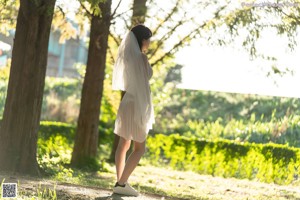 A woman in a white dress standing next to a bike.