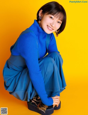 A woman in a blue sweater is posing for a magazine.