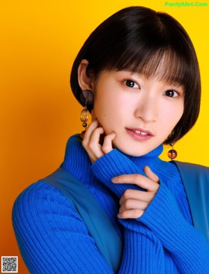 A woman in a blue sweater and blue pants posing for a picture.