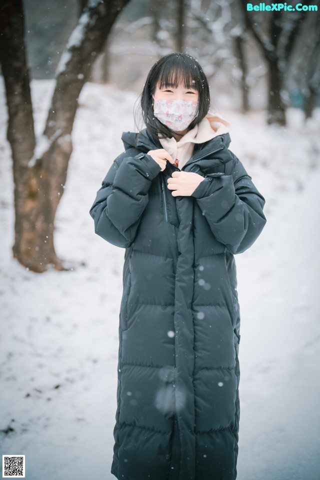 A woman wearing a face mask standing in the snow.