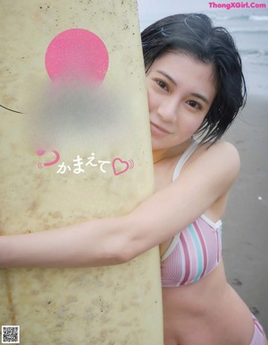 A woman in a bikini sitting on a surfboard in the ocean.