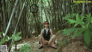 A woman in a black dress standing in a bamboo forest.