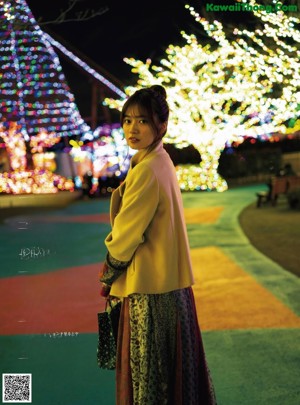 A woman holding a red gift box in front of a ferris wheel.