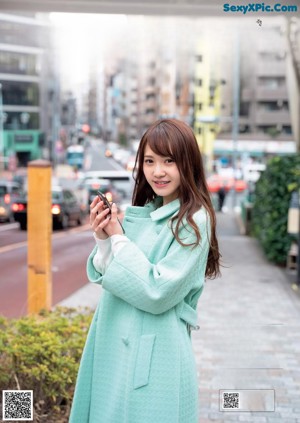 A woman in a blue shirt is holding a bottle of water.