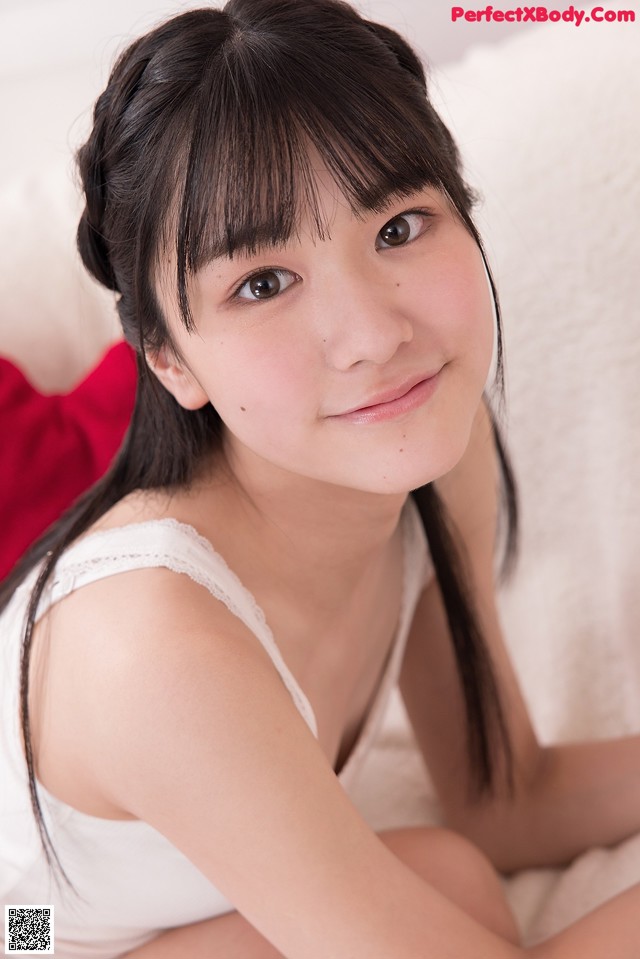 A young woman sitting on top of a white couch.