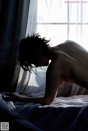 A woman standing in a doorway with a light coming through it.