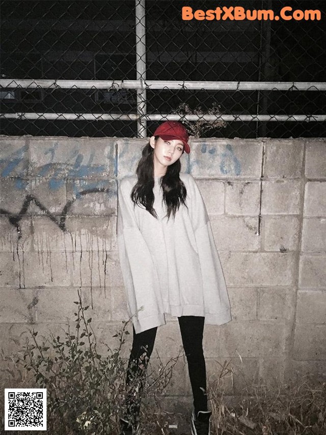A woman standing in front of a wall wearing a red hat.
