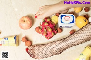 A woman sitting on the floor next to a bunch of fruit.
