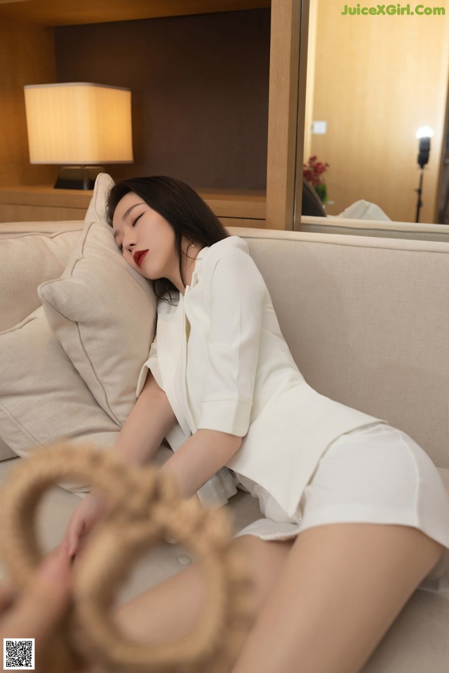 a woman laying on top of a couch next to a lamp