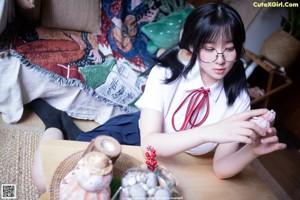 A woman in a school uniform is sitting on a bed.