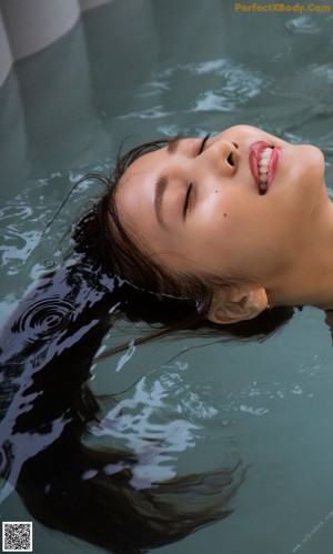 A woman in a bikini laying in a bathtub.