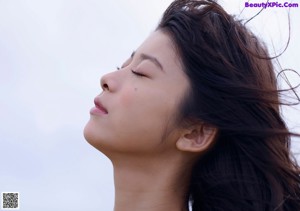 A woman in a purple bikini posing in front of a rock.