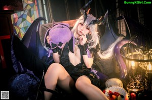 A woman dressed as a witch sitting on a bed.
