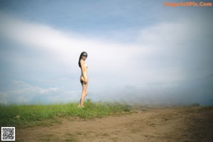 A naked woman in a white bathing suit sitting on a rock.