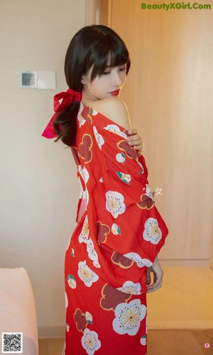 A woman in a red kimono laying on a bed.