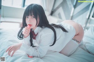 A woman in a white thong laying on a bed.