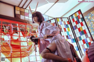 A woman in a kimono standing in front of a stained glass window.