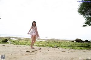 A woman in a floral dress sitting on a rock.