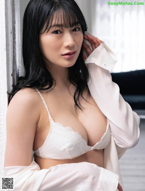A woman in a nude lingerie standing in a bathtub.
