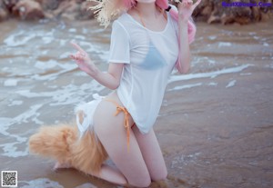 A woman with pink hair wearing a straw hat on the beach.