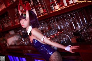 A woman dressed as a devil sitting at a bar.