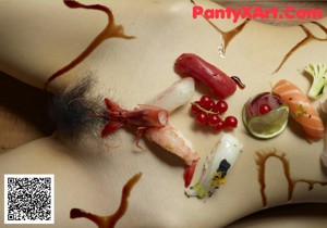 A naked woman laying on a wooden floor covered in sushi.