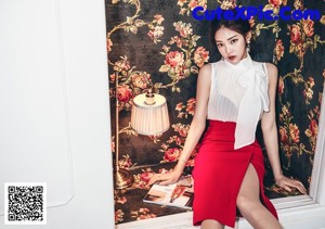 A woman in a purple shirt and white skirt posing for a picture.