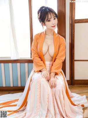 A woman in an orange kimono is posing for the camera.
