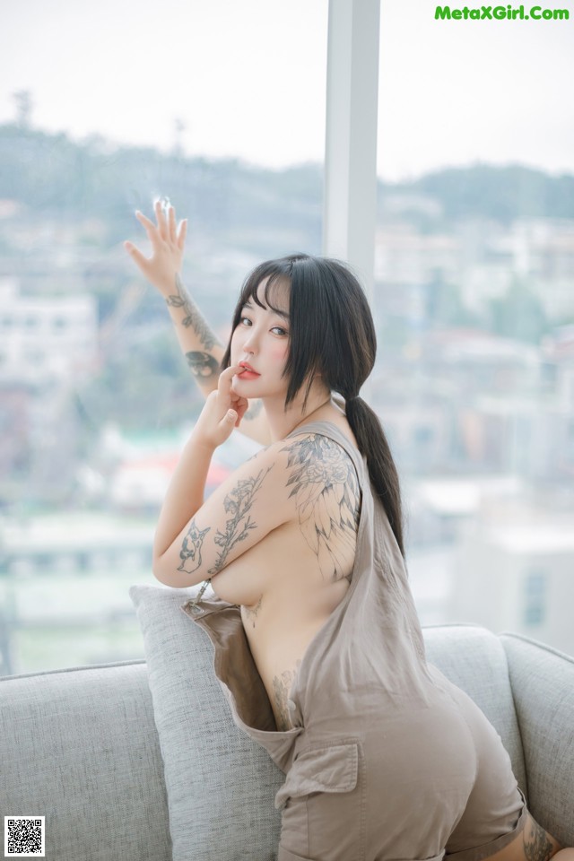 A woman sitting on a couch with a tattoo on her arm.