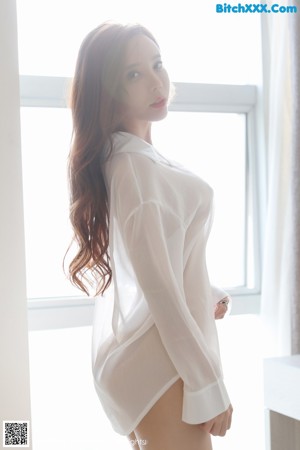 A woman in a white shirt and red skirt sitting on the floor.