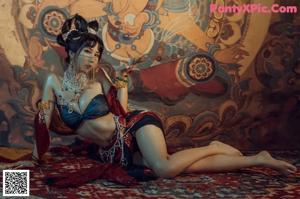 A woman sitting on a rug in front of a painting.