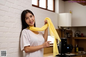 A woman in a yellow shirt and white shorts holding a straw hat.